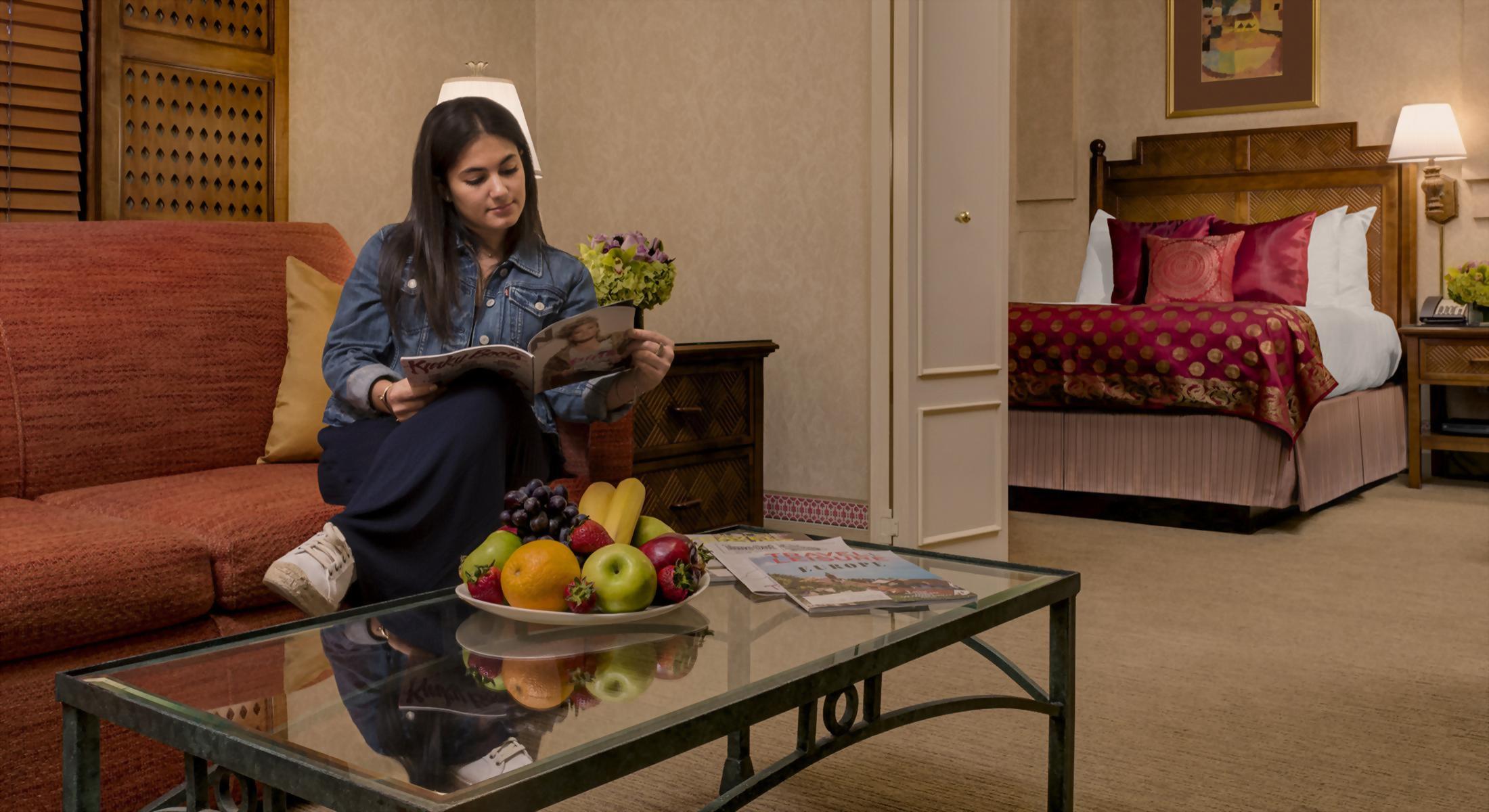 Woman reading magazine on sofa in living room area of mini suite