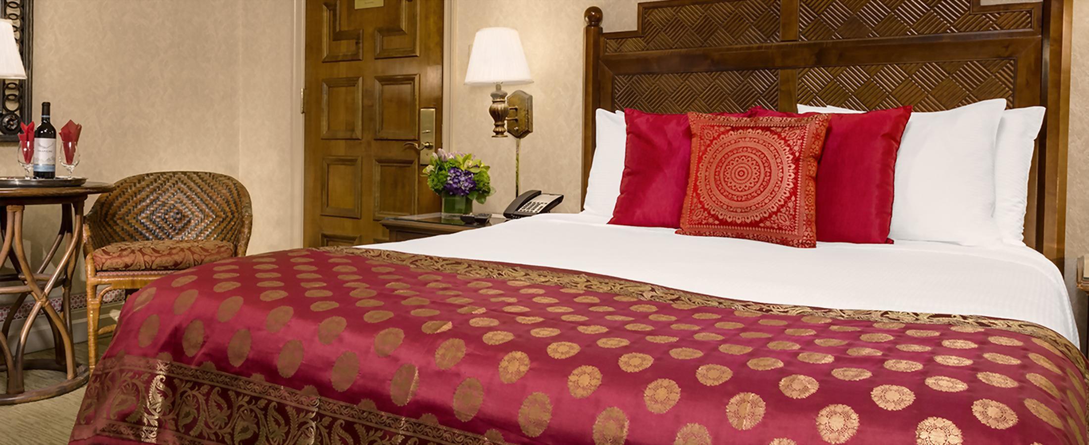 A queen size bed and bistro table in the Deluxe Queen room.
